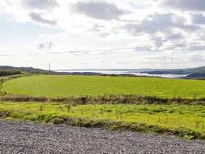 A rural landscape with a gravel road, green fields, and a distant body of water under a partly cloudy sky. - Drumwall - Sea Glass (Gatehouse of Fleet)