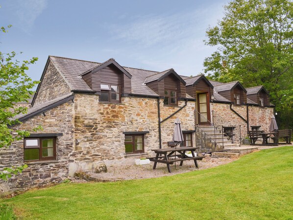A stone building with a wooden exterior, a picnic table, and a bench.