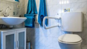 A bathroom with a white sink, mirror, and toilet. There are blue towels hanging on the wall.