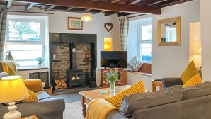 A cozy living room with a fireplace, sofa, TV, and a window with a view.