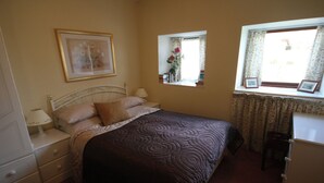 A bedroom with a bed, nightstands, a dresser, a window with curtains, and a framed picture on the wall.