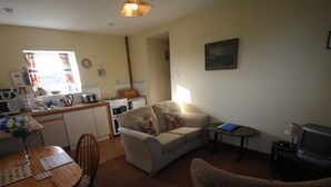 A compact living space with a kitchenette, a sofa, a dining table, and a television.