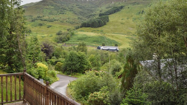 Une vue pittoresque d’un paysage montagneux, avec une terrasse en bois et une maison située dans la vallée.