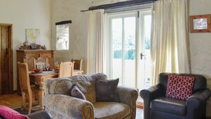 Un salon chaleureux avec un fauteuil à motifs, un canapé en cuir et un fauteuil foncé agrémenté d’un coussin à motifs. On aperçoit une table à manger en bois avec des chaises à l’arrière-plan.