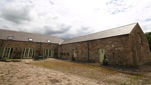 Un bâtiment en pierre doté d’une cour, d’une galerie couverte et d’un petit espace aménagé pour s’asseoir.
