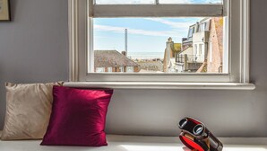 A room with a window overlooking a cityscape, a bed with a beige and a red pillow, and a pair of binoculars on the windowsill. - 1 bedroom accommodation in Hastings (Hastings)