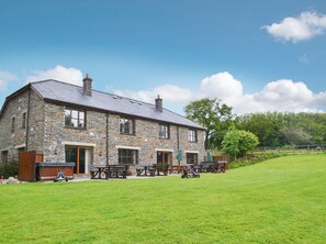 A stone building with a metal roof, wooden benches, and picnic tables in a grassy area. - 4 bedroom accommodation in Dunterton, near Tavistock (Dunterton, near Tavistock)