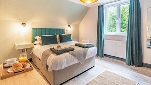 A bedroom with a bed, bedside tables, a window with curtains, and a hanging light fixture. - 3 bedroom accommodation in Llanerfyl, near Welshpool (Llanerfyl, near Welshpool)