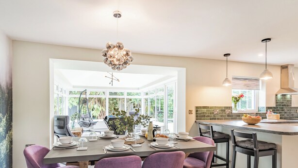 A modern kitchen with a dining area, featuring a large island, pendant lights, and a hanging light fixture. - 3 bedroom accommodation in Llanerfyl, near Welshpool (Llanerfyl, near Welshpool)