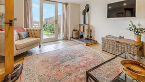 Ein modernes Wohnzimmer mit einer Couch, einem Kamin, einem Fernseher und einem großen Fenster.