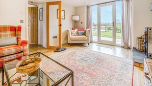 Ein Wohnzimmer mit einer Couch, einem Glastisch, einem Sessel und einem Kamin.