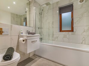 A bathroom with a toilet, a glass shower enclosure, a bathtub, and a mirror.