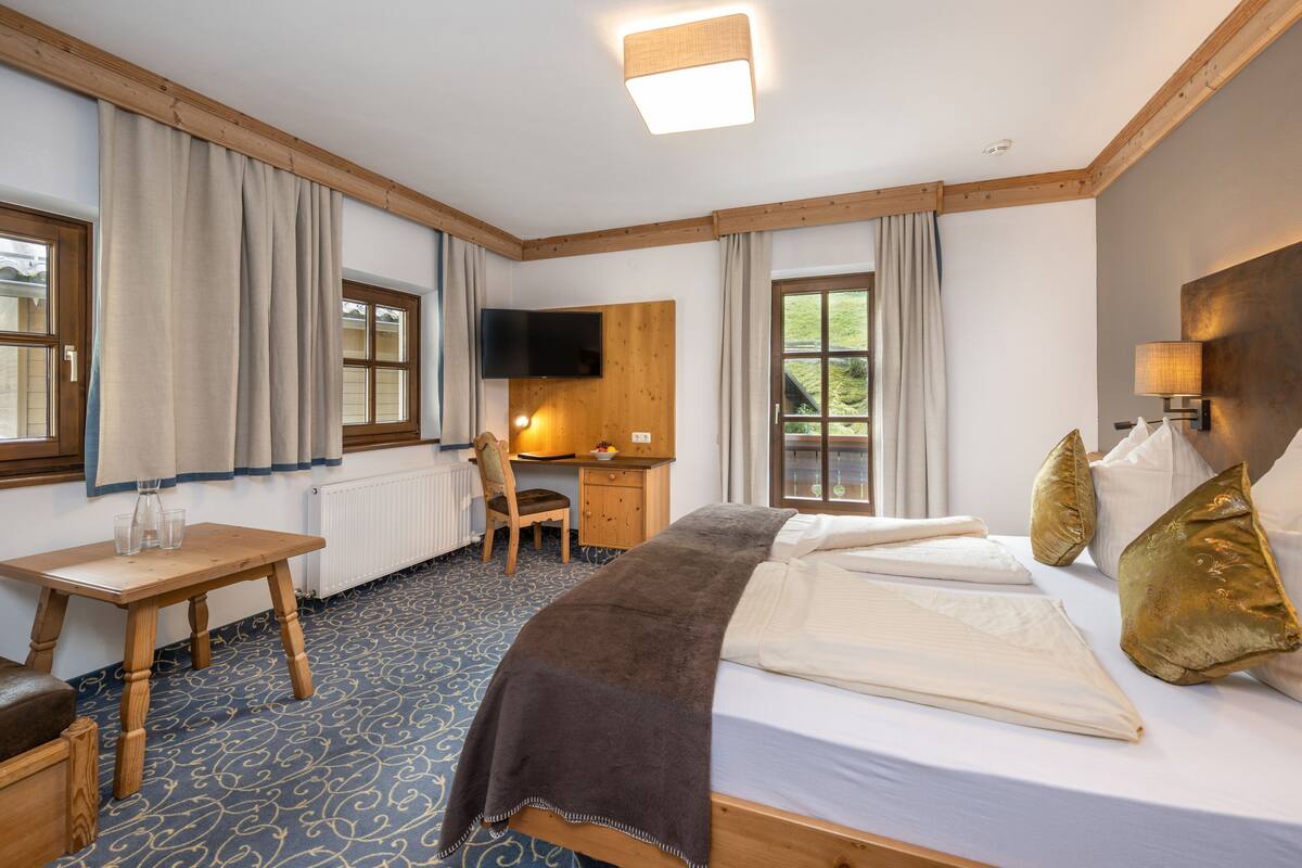 Ein Hotelzimmer mit Bett, Schreibtisch, Stuhl, Fernseher und Fenster.