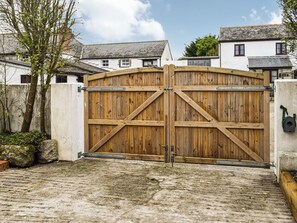 A wooden gate with a metal latch, a concrete wall, and a paved ground. - 1 bedroom accommodation in Helston, near Helston and the Lizard Peninsula (Helston, near Helston and the Lizard Peninsula)