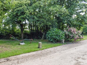 A garden with a variety of plants, a stone wall, and a metal sculpture. - 1 bedroom accommodation in Helston, near Helston and the Lizard Peninsula (Helston, near Helston and the Lizard Peninsula)