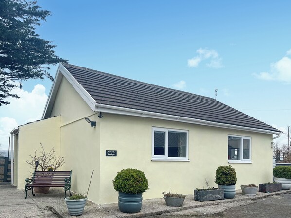 A single-story building with a sloped roof, a nameplate reading "Kevan's Lodge," and several potted plants in front. - 1 bedroom accommodation in Llanarthney (Llanarthney)