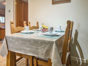 A dining table set with white plates, cups, and a fruit bowl. - 1 bedroom accommodation in Llanarthney (Llanarthney)