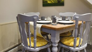 Une table à manger avec quatre chaises, un tableau accroché au mur et un radiateur en dessous.