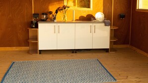 Un intérieur en bois avec un meuble blanc, un tapis à motifs bleus et une fenêtre donnant sur un paysage agréable.