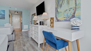 A modern hotel room with a white desk, blue chair, and a large painting of a beach scene. - Peaceful Bay 6386-Bay View-Sleeps 4 (Miramar Beach)