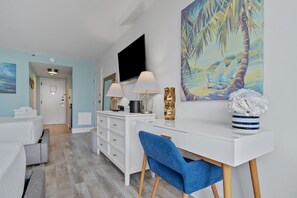 A modern hotel room with a white desk, blue chair, and a large painting of a beach scene. - Peaceful Bay 6386-Bay View-Sleeps 4 (Miramar Beach)