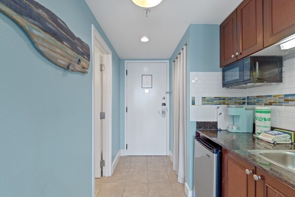 A kitchen with a microwave, coffee maker, and paper towel dispenser. - Peaceful Bay 6386-Bay View-Sleeps 4 (Miramar Beach)