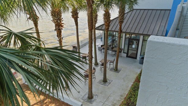 A rooftop terrace with palm trees, outdoor seating, and a view of the water. - Peaceful Bay 6386-Bay View-Sleeps 4 (Miramar Beach)