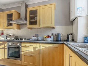Cozinha moderna com armários de madeira, eletrodomésticos de aço inoxidável e uma tigela de frutas no balcão.