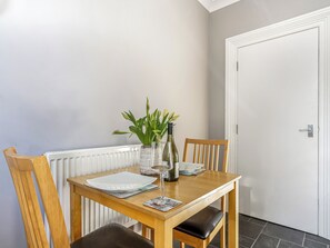 A dining table with chairs, a vase with flowers, a wine bottle, and a plate. - Immaculate Sea View Apartment - Desirable West Cliff Location. (Whitby)