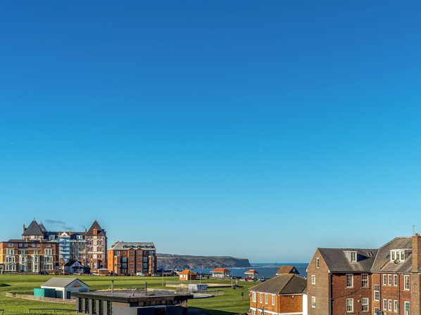 A coastal town with a mix of residential and commercial buildings, including a large hotel with multiple floors and a prominent entrance.