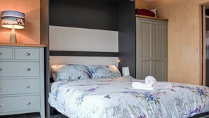 A bedroom with a bed, a nightstand, a wardrobe, and a lamp.