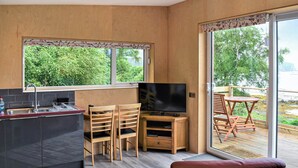 A modern kitchen with a TV, wooden chairs, and a dining table.