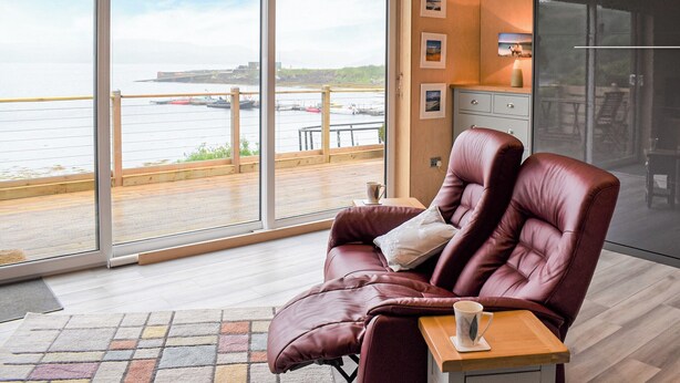A modern room with a large sliding glass door leading to a balcony with a view of the water and boats.