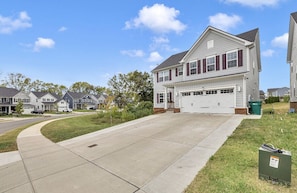 A two-story residential house with a garage, a driveway, and a well-maintained lawn.