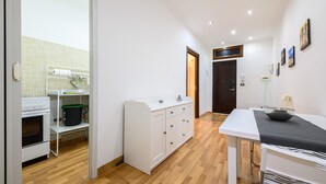 Une cuisine moderne avec des meubles blancs, un four encastré et un coin repas comprenant une table et des chaises.