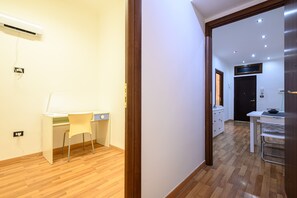 A modern room with a wooden floor, a desk with a chair, a bed, and a wardrobe.