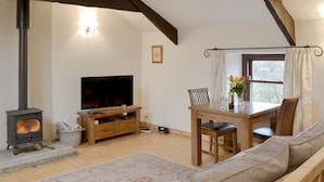 Una sala de estar acogedora con chimenea, televisor, mesa de comedor con sillas y sofá.
