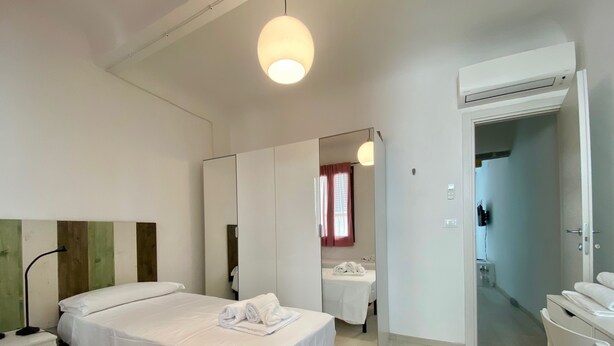 Une chambre d’hôtel avec un lit, un bureau, un miroir et une armoire.