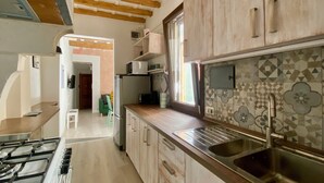 Une cuisine avec des meubles en bois, un évier en acier inoxydable et une cuisinière à gaz.