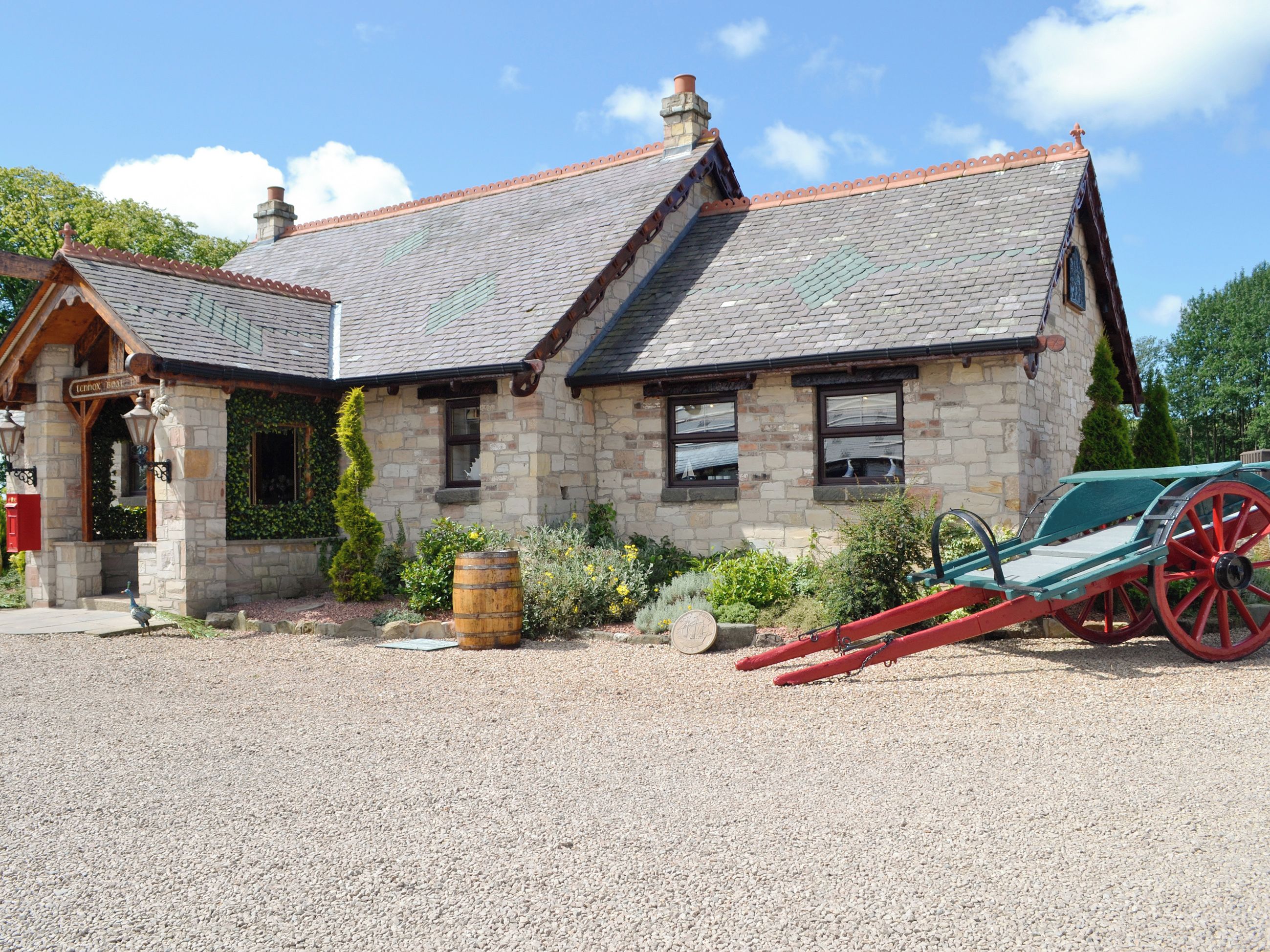A stone building with a sloped roof, a small porch, and a carriage in front.
