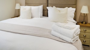 A neatly made bed with pillows and a folded blanket, a bedside table with a lamp, and a dresser with drawers. - Salem Porter- UK34814 (Wainfleet, near Skegness)