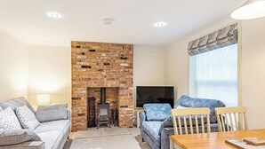 A living room with a brick fireplace, two sofas, a TV, and a dining table. - Salem Porter- UK34814 (Wainfleet, near Skegness)