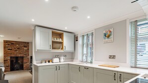 A modern kitchen with grey cabinets, a brick fireplace, and a window with blinds. - Salem Porter- UK34814 (Wainfleet, near Skegness)