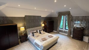 Een slaapkamer met een groot bed, twee nachtkastjes, een garderobe en een raam met gordijnen.