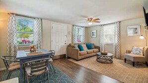 A cozy living room with a sofa, coffee table, and dining area with chairs and a table. - East Riverside Downtown Bungalow (Port Richey)