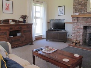 A living room with a television, fireplace, and a wooden cabinet.