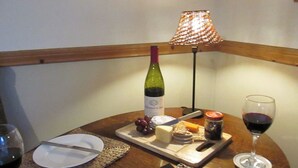 A table with a bottle of wine, cheese, grapes, a book, and a glass of wine. - Robin Cottage Nr Rothbury (Weldon Bridge, near Rothbury)