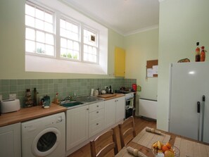 A kitchen with a washing machine, a sink, a stove, and a refrigerator.