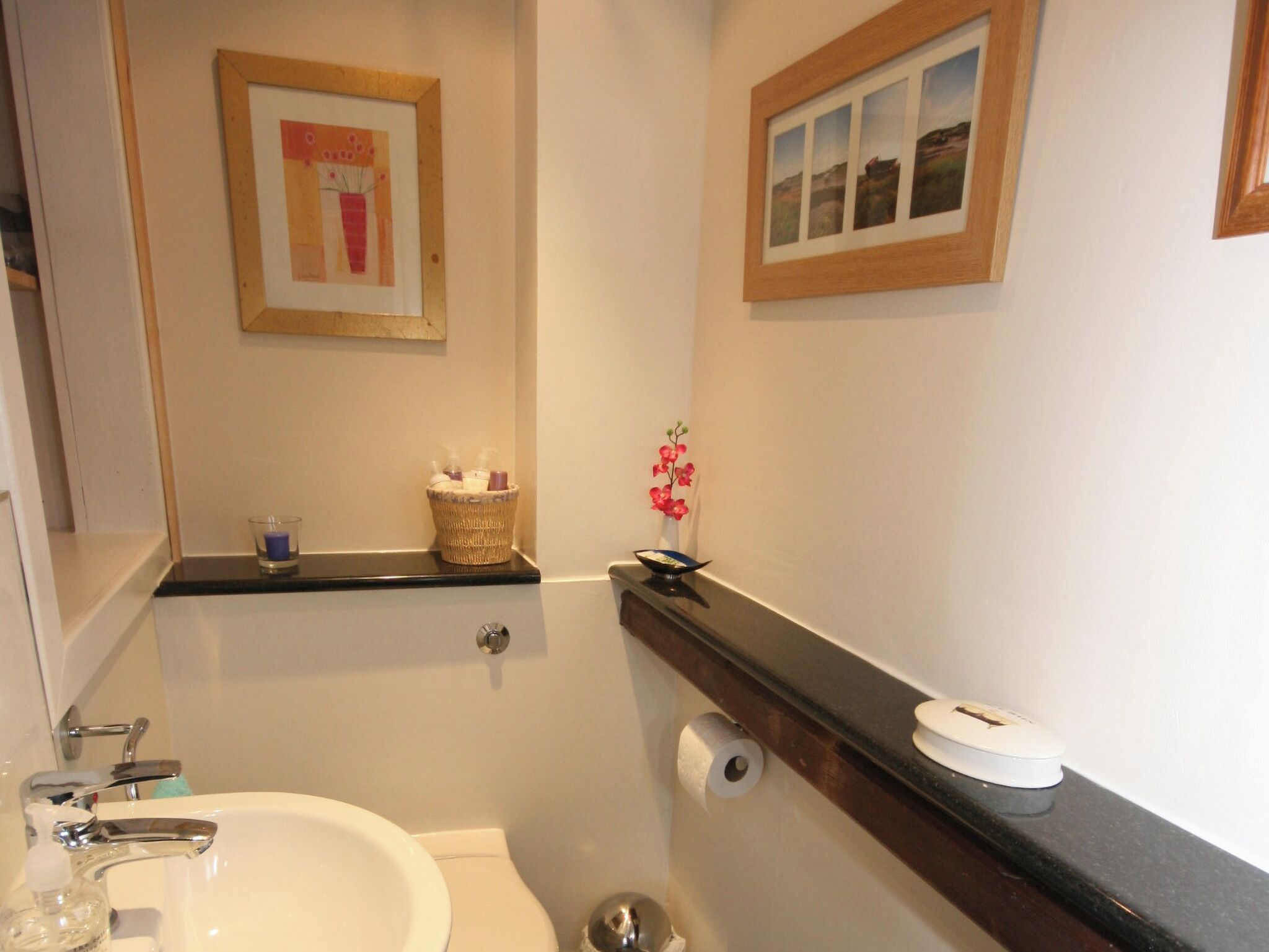 Une salle de bain avec un lavabo, des toilettes et des tableaux encadrés au mur.