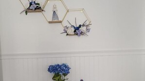 A small table with a vase of flowers and a blue bottle, a decorative wall piece with a lighthouse, and a 'yum' sign. - Great Location - 3 miles to Cedar Point Park, 2.8 miles to CP Sports  Force Park (Sandusky)